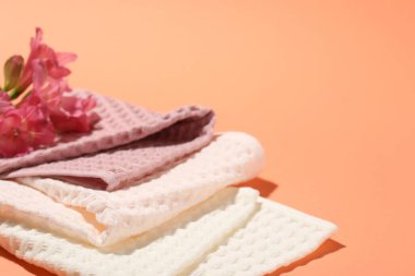 Mercan zemininde katlanmış waffle havluları ve çiçekler, yakın plan. Metin için boşluk