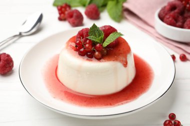 Lezzetli panna cotta, böğürtlen, sos ve nane ile beyaz ahşap masa, yakın plan.