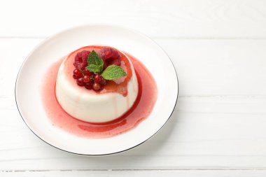 Lezzetli panna cotta, böğürtlen, sos ve nane ile beyaz ahşap masa, yakın plan.