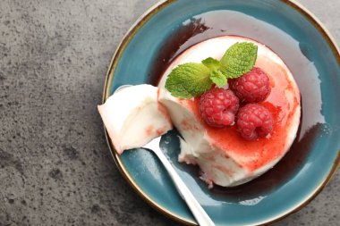 Lezzetli panna cotta, böğürtlen, sos ve nane. Gri desenli masa, üst manzara.