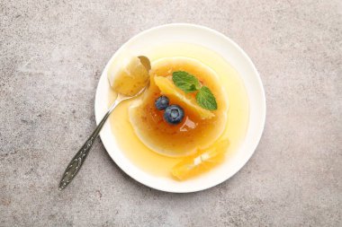 Portakallı, böğürtlenli ve açık gri masadaki nane aromalı panna cotta.