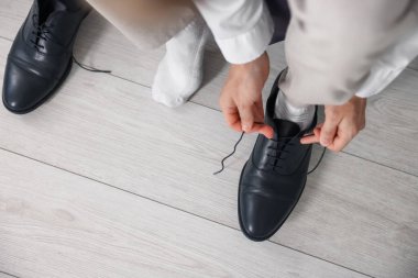 Hazırlanıyor. Genç adam evde şık ayakkabılar giyiyor, yakın plan.