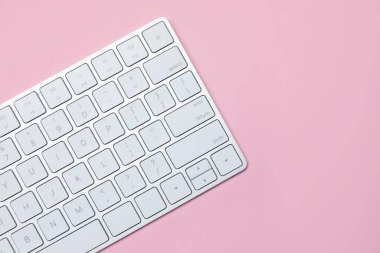 Pembe arka planda modern beyaz kablosuz klavye, üst manzara. Metin için boşluk