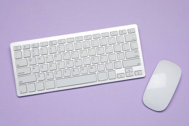 Mor arkaplanda beyaz kablosuz klavye ve fare, üst görünüm