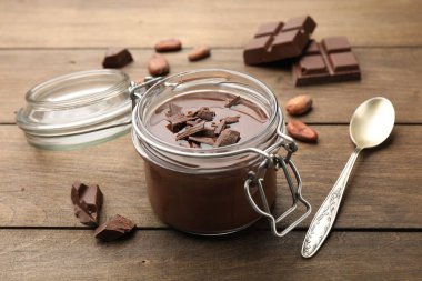 Cam kavanozda nefis çikolata panna cotta, ahşap masada fındık ve kaşık, yakın plan.