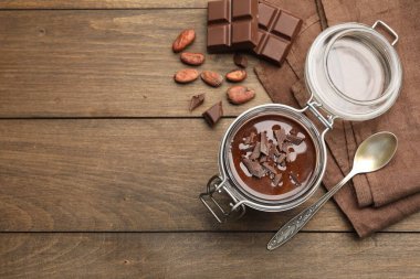 Cam kavanozda nefis çikolatalı panna cotta, tahta masada fındık ve kaşık, düz yatak. Metin için boşluk