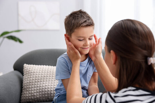 Мама поддерживает своего грустного сына на диване дома