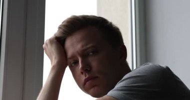 Pencerenin yanında üzgün, yorgun bir adam var. Depresyon