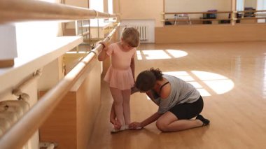 Gülümseyen bale öğretmeni bar stüdyosunda küçük bir kızla çalışıyor.