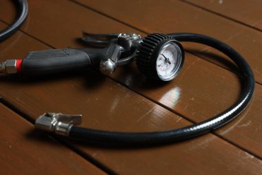 Ahşap arka planda göstergesi olan bir lastik enflasyon silahı, yakın plan.