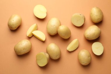 Açık kahverengi arka planda taze çiğ patates, düz uzanmış.