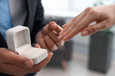 Nişan yüzüklü bir adam içeride kız arkadaşına evlenme teklif ediyor.