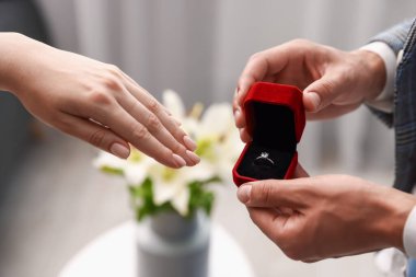 Nişan yüzüklü bir adam içeride kız arkadaşına evlenme teklif ediyor.