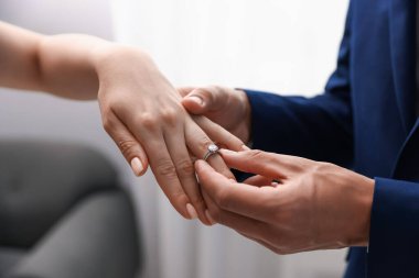 Evlenme teklif ediyorum. Adam içeride kız arkadaşının parmağına nişan yüzüğü takıyor.