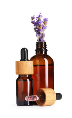 Lavanta yağı, çiçekli ve damlatıcılı şişelerde beyaza izole edilmiş.