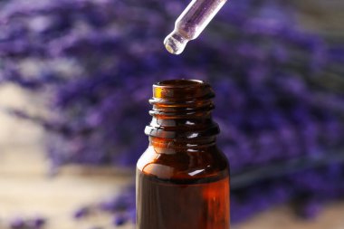 Lavanta yağı şişeye damlıyor. Arka plan bulanık, yakın plan.