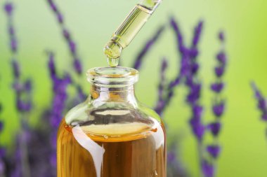 Lavanta yağı şişeye damlıyor. Arka plan bulanık, yakın plan.