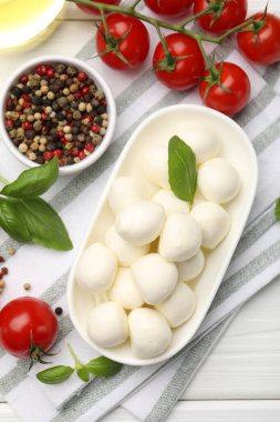 Lezzetli mozzarella peyniri, domates, fesleğen ve baharatlar beyaz ahşap masa üzerinde, düz yatıyordu.