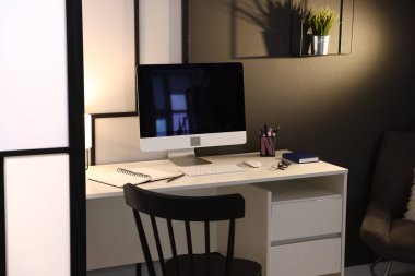 Ofiste bilgisayar, kırtasiye ve gözlüklü bir masa. İç tasarım