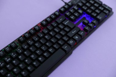 Mor arkaplanda RGB ışıklandırması olan modern bilgisayar klavyesi, yakın plan