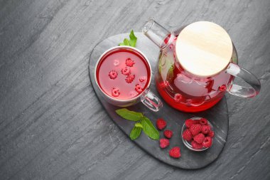 Cam fincanda Aromatik ahududu çayı, çaydanlık, böğürtlen ve nane, siyah masa, üst manzara. Metin için boşluk