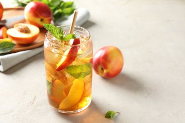 Buzlu şeftali çayı, bardakta nane şekeri ve beyaz masada taze meyveler, yakın plan. Metin için boşluk