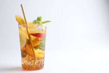 Limonlu buzlu çay, beyaz arka planda şeftali ve nane, yakın plan. Metin için boşluk