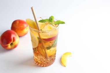Limonlu buzlu çay, beyaz arka planda şeftali ve nane, yakın plan. Metin için boşluk