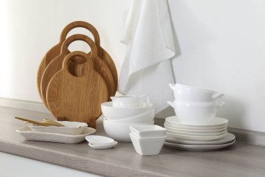 Mutfakta farklı beyaz bulaşık takımları ve tahta kesme tahtaları var.