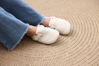 Hasır üzerinde yumuşak beyaz terlik giyen kadın, yakın plan.