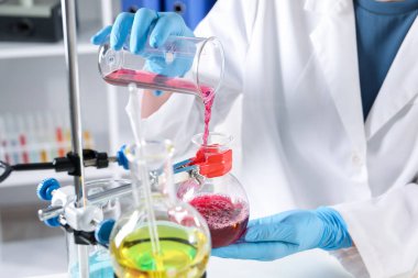 Bilim adamı cam şişeye örnek dolduruyor. Kapalı mekanda, yakın planda. Çözüm kimyası