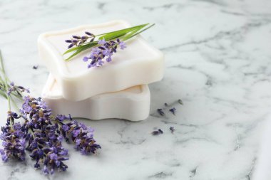 Sabun barları ve lavanta çiçekleri beyaz mermer masada, yakın plan. Metin için boşluk