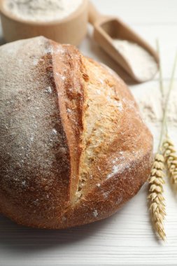 Taze ekmek, un ve çiviler beyaz ahşap masada, yakın plan.