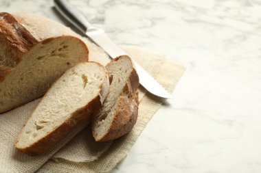 Beyaz mermer masada taze ekmek ve bıçak parçaları, yakın plan. Metin için boşluk