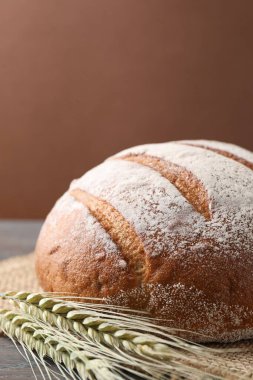 Taze ekmek ve yeşil buğday başakları masada, yakın plan.