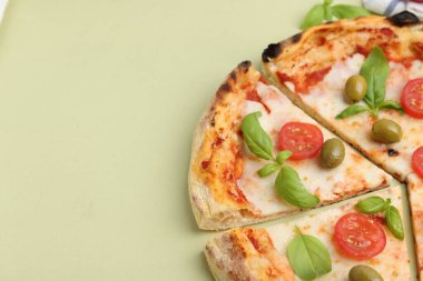 Açık yeşil arka planda domatesli, fesleğenli ve zeytinli pizza, yakın plan. Metin için boşluk