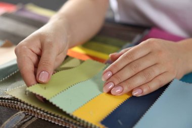 Kadın farklı örnekler arasından kumaşı seçiyor, kapalı alanda, yakın plan.