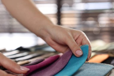 Kadın farklı örnekler arasından kumaşı seçiyor, kapalı alanda, yakın plan.