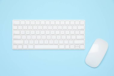Açık mavi zemin üzerinde modern beyaz kablosuz klavye ve fare, üst görünüm
