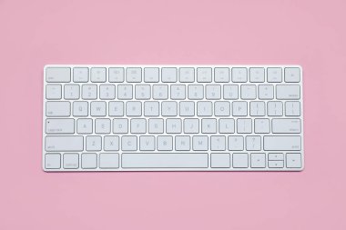 Pembe arka planda modern beyaz kablosuz klavye, üst görünüm
