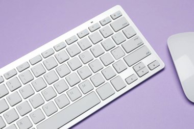 Menekşe arkaplanda beyaz kablosuz klavye ve fare, üst görünümde