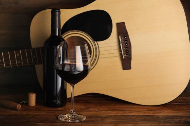 Akustik gitar, şişe ve bir bardak kırmızı şarap.