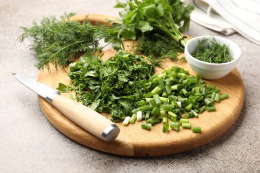 Gri masada farklı taze otlar ve bıçak, yakın plan.