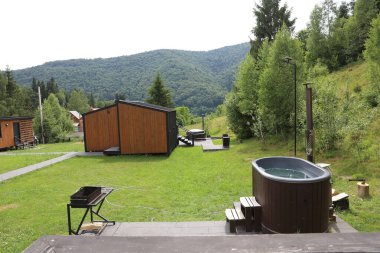 Sıcak su dolu küvet ve dağlarda lüks bir tatil köyünde binalar.