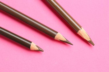 Pembe arka planda farklı kaş kalemleri, düz yatış.