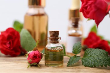 Gerekli yağlar, kırmızı güller ve ahşap masada bitkiler, yakın plan.