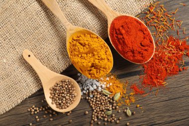 Tahta masada, düz yerde, kaşıklardaki farklı aromatik baharatlar.