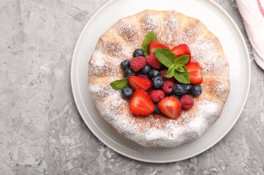 Gri desenli masada pudra şekeri ve böğürtlenli Lezzetli kek.