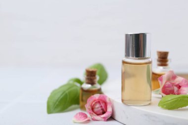 Kozmetik ürünleri, güller ve fesleğenler beyaz masada, yakın plan. Metin için boşluk