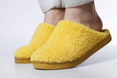 Hafif sarı terlikli kadın beyaz arka planda, yakın plan.